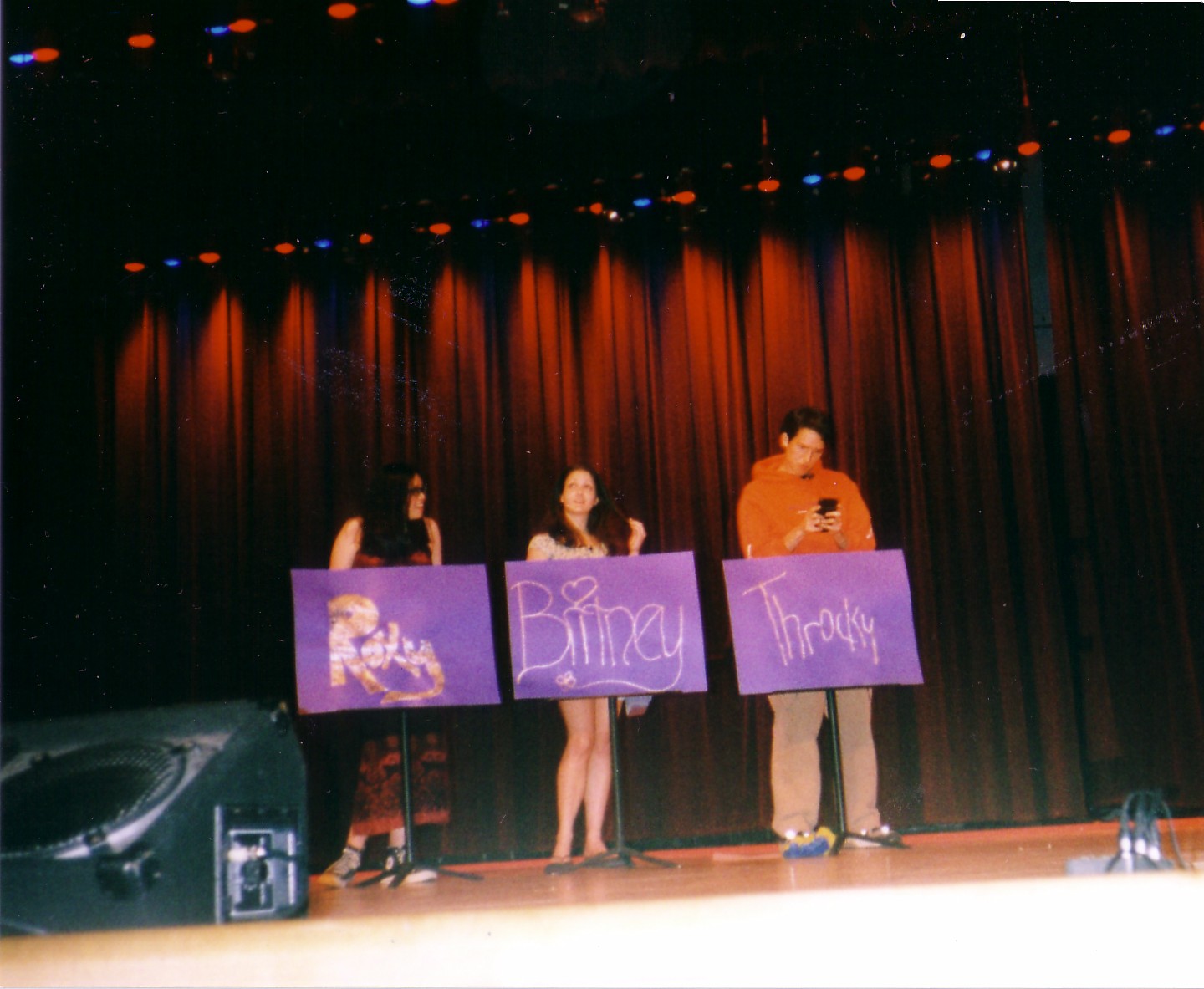 Throcky, Roxy, and Britney Spears standing behind their podiums, Throcky playing calculator games